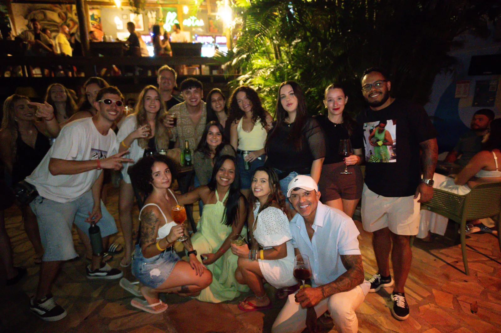 Grupo de amigos reunido numa festa do Floresta Bar, todos com drink na mão