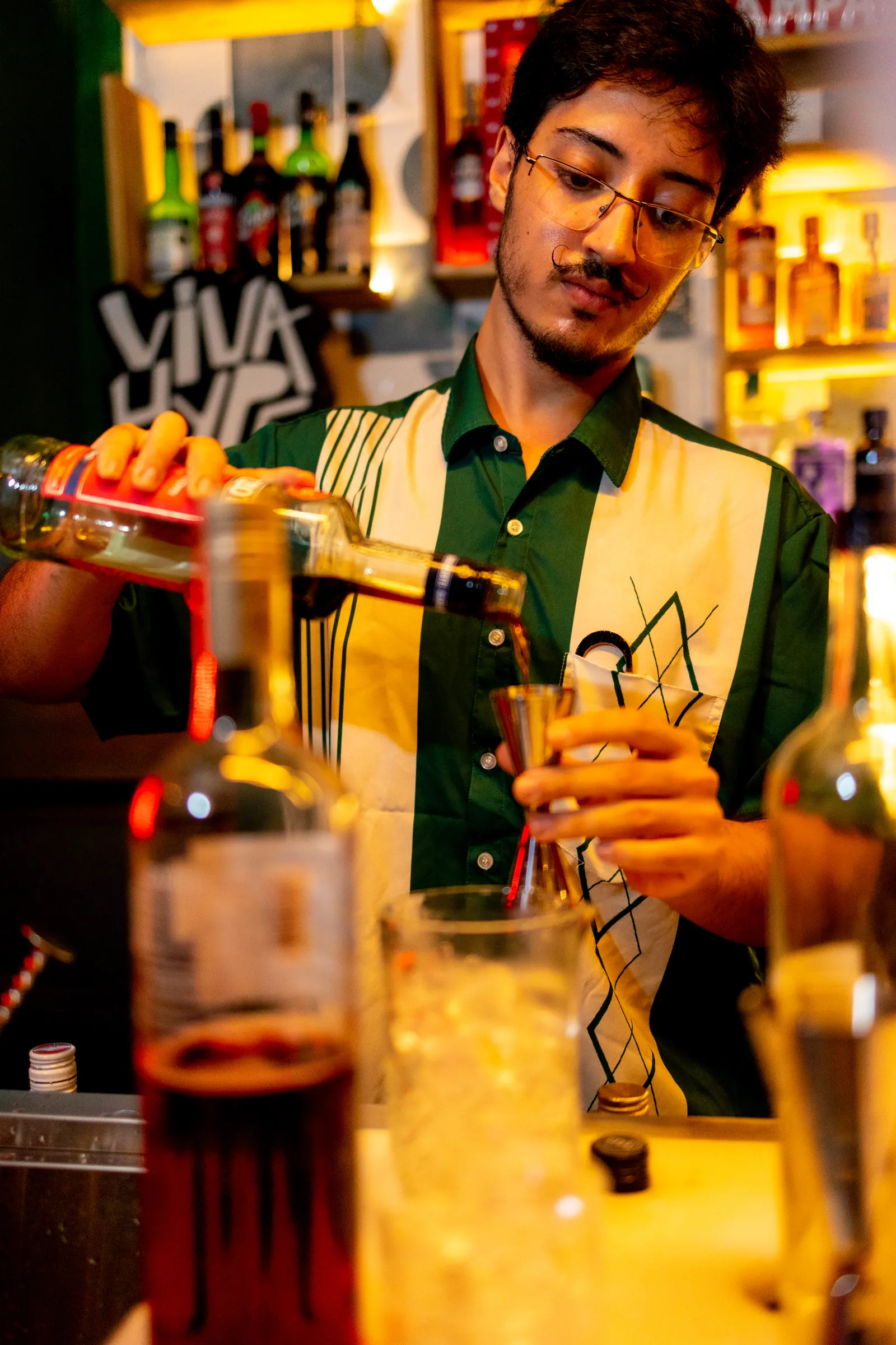 Bartender do Na Moita Bar preparando um drink autoral, servindo a dose com capricho