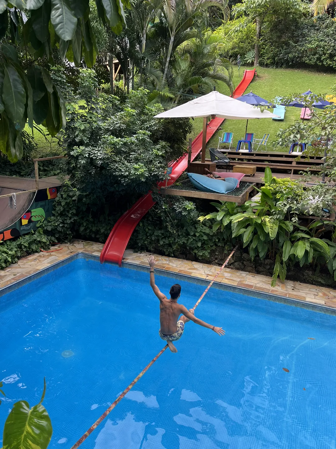 Hóspede atravessando o slackline sobre a piscina do Hostel da Vila em Ilhabela