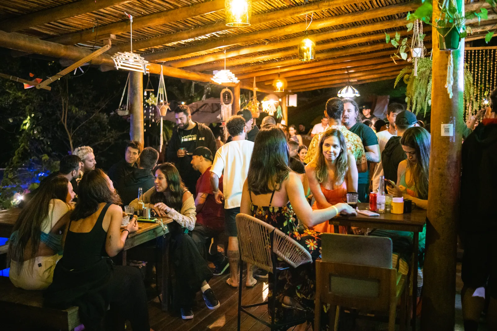 Floresta Bar iluminado à noite com hóspedes nas mesas no Hostel da Vila em Ilhabela