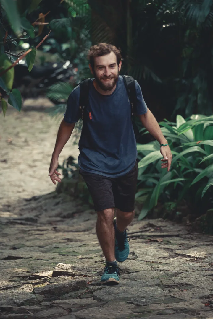 Mochileiro sorrindo numa trilha do Hostel da Vila em Ilhabela